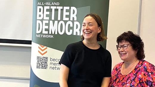 Photo of Rebekah McCabe and Nivek Thompson smiling in front of a Better Democracy Network Banner